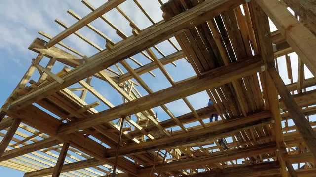 Wooden house construction site with sun shining on blue sky
