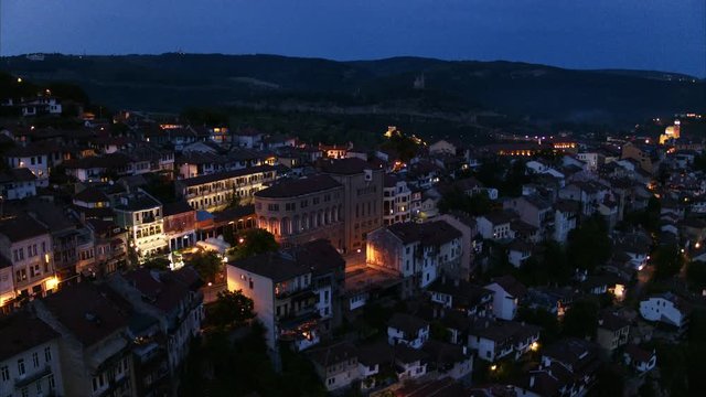 Wide flyover shot approaching houses on hillside at night / Veliko Tarnovo, Bulgaria
