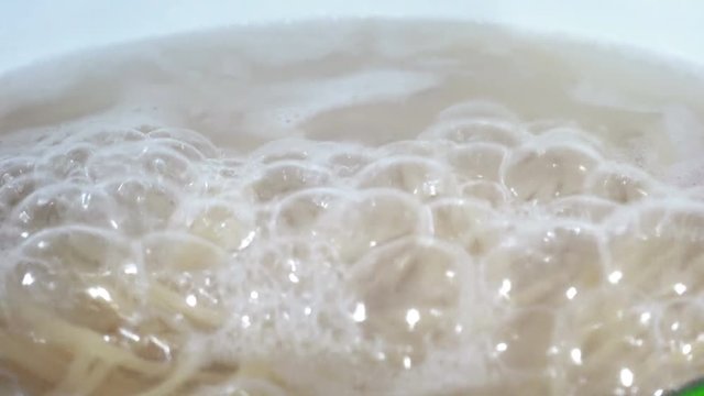 Boiling water with spaghetti in the steel pan, closeup
