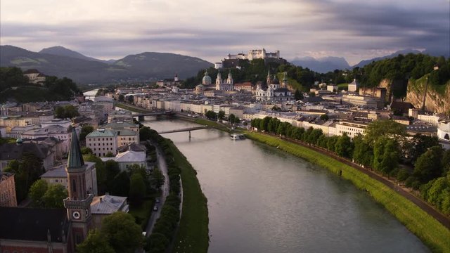 Wide aerial shot of river in city at sunset / Salzburg, Austria