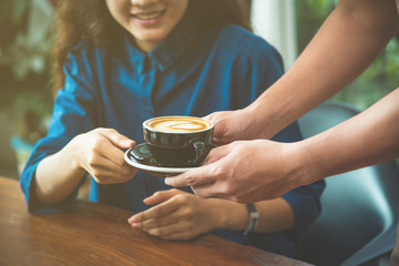 Hands of waiter serving a cup of coffee to customer with vintage filter