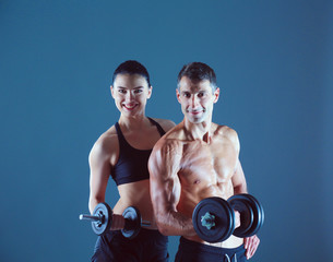 Fototapeta na wymiar Athletic man and woman with a dumbells. Personal fitness instructor. Personal training.