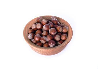 hazelnut in a shell in a brown wooden plate isolated on a white background top view