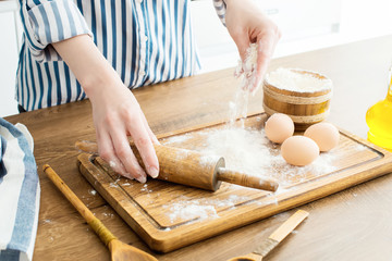 Female hands making dough on kitchen background