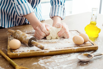 Female hands making dough on kitchen background
