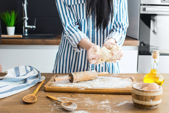 Female hands making dough on kitchen background