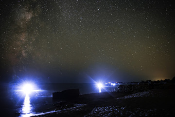 Sea landscape of the sandy beach and ocean with night divers against the background of the starry sky