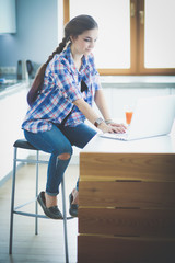 Beautiful young smiling female doctor sitting at the desk and writing.