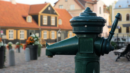Green manual water pump in the town. Kuldiga. Latvia