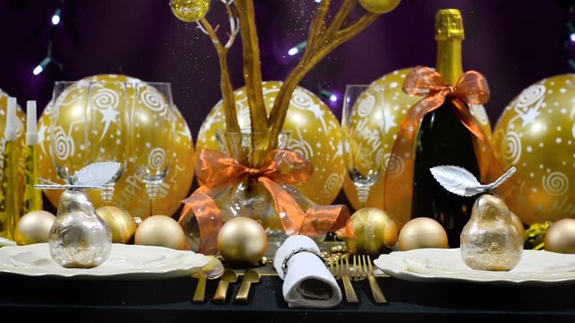 New Years Eve party dinner table with gold, white and black theme with Christmas fairy lights background, with downward glittering light beams.