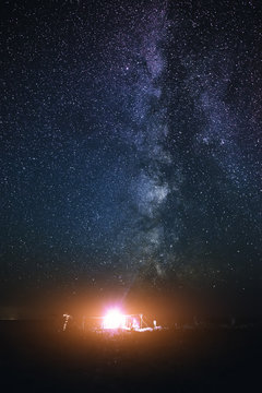 Illuminated tent on the beach against the background of a bright sky with milky way