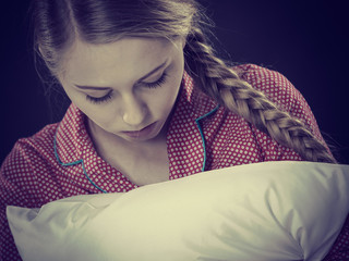 Sad depressed girl in bed gripping pillow
