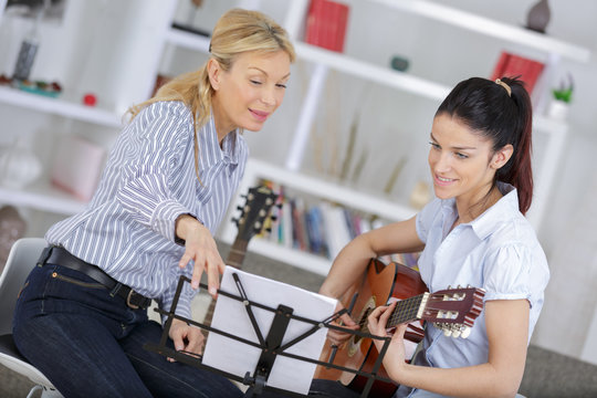 woman learning to play guitar with teacher