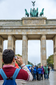 Tourist macht Foto mit Smartphone vor Brandenburger Tor in Berlin