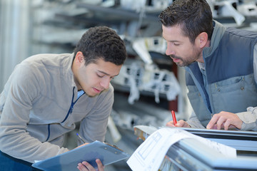engineer taking notes from manager at control room