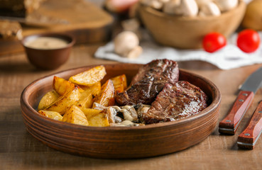 Plate with steak Diane and vegetable garnish on wooden table