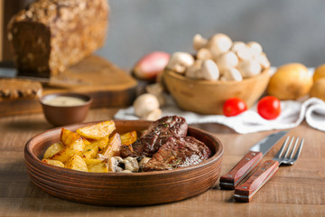 Plate with steak Diane and vegetable garnish on wooden table