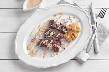 Plate with steak Diane on white wooden table
