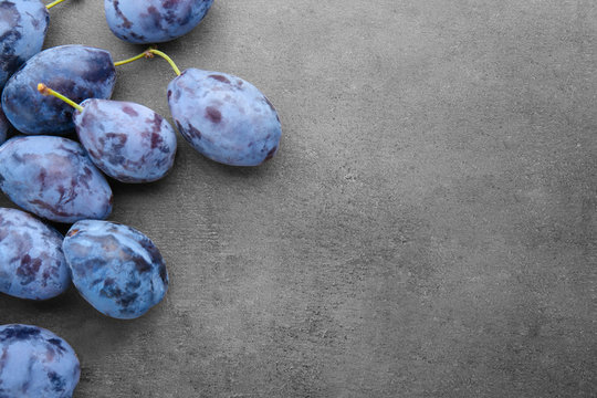 Fresh ripe plums with leaves on grey background