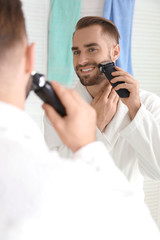 Morning of handsome young man shaving in bathroom