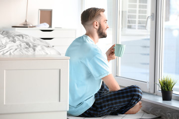 Morning of handsome young man drinking coffee at home
