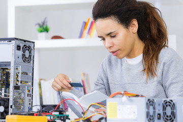 female technician with dismantled computer and instruction book