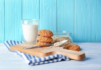 Delicious oatmeal cookies with glass of milk on wooden board