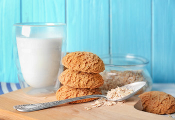 Delicious oatmeal cookies with glass of milk on wooden board