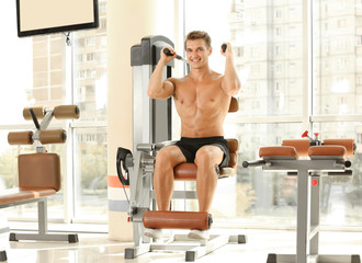 Fototapeta premium Sporty young man training in gym