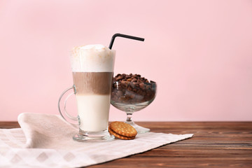 Glass with latte macchiato on table against color background