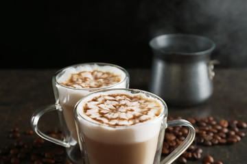 Glass cups with latte macchiato on table against black background