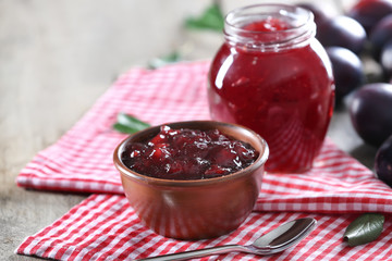 Bowl of delicious plum jam on table