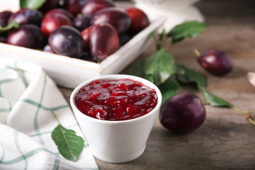 Bowl of delicious plum jam on table