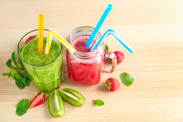 Glassware with delicious kiwi and strawberry smoothies on light background
