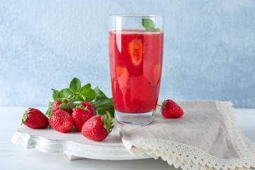 Glass with delicious strawberry smoothie on light background