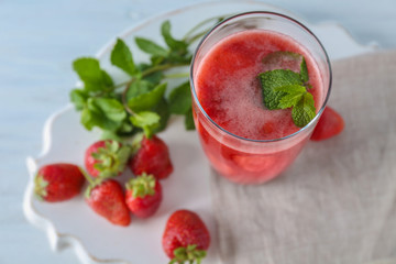 Glass with delicious strawberry smoothie on light background