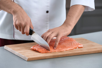 Chef cutting fresh salmon fillet in kitchen