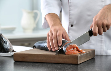 Chef cutting fresh salmon in kitchen