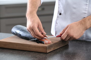 Chef cutting fresh salmon in kitchen