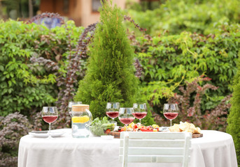 Food and wine served on table for barbecue party in garden