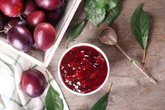 Bowl of delicious plum jam on table