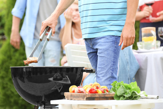 Man cooking tasty steaks on barbecue grill, outdoors