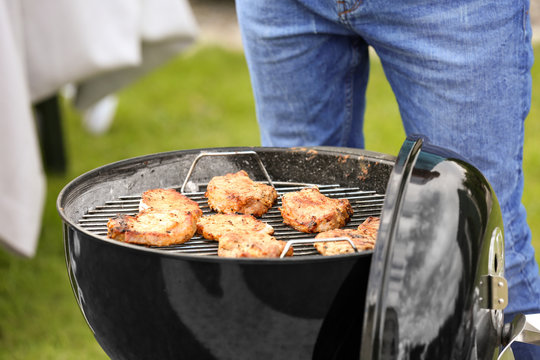 Man cooking tasty steaks on barbecue grill, outdoors