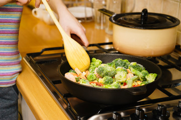 Girl frying vegetables on pan