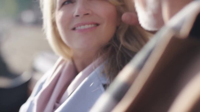Happy mature couple sitting on a bench talking, in slow motion