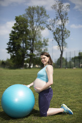 Young pregnant woman exercises with fitball in the gym