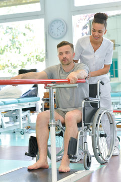 physiotherapist helping man in wheelchair doing exercises