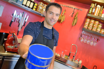 Man in deli holding forth a blue tin