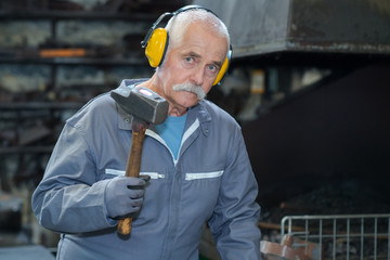 experienced blacksmith using hammer in his workshop