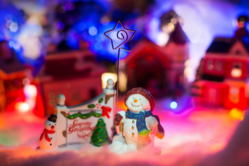 Miniature festive background, Fairytale scenery with snowman holding star Singing In Choir Together. Miniature Christmas Village. Christmas concept,